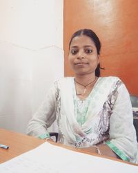 Portrait of smiling young woman standing against wall