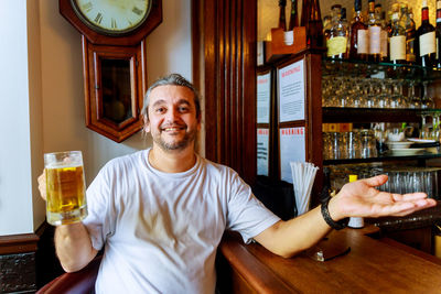 Portrait of a smiling young man with drink in restaurant