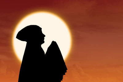 Silhouette man standing against orange sky