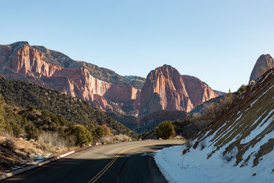 Road by mountains against clear sky