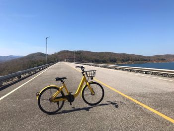 Bicycle parked on road against blue sky