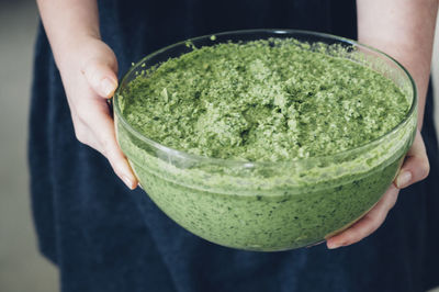 Midsection of woman holding pesto sauce in glass bowl