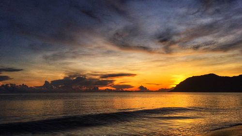 Scenic view of sea against dramatic sky during sunset