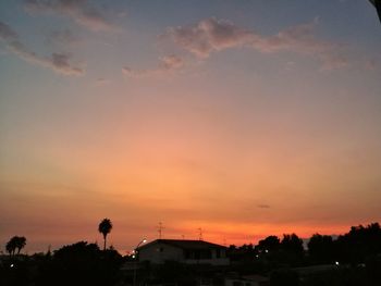 Silhouette houses and trees against sky at sunset