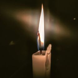 Close-up of lit candle in the dark