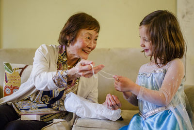 A smiling girl in princess costume opens up gift from her grandmother