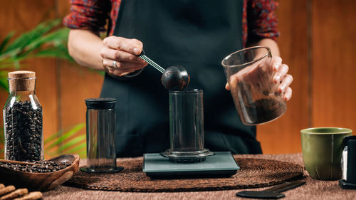 Midsection of woman measuring ground coffee in cafe