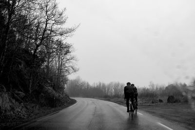 Rear view of people riding bicycles on road