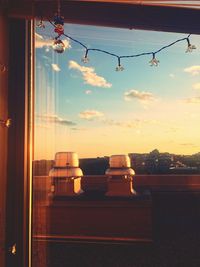 Close-up of illuminated lamp hanging against sky at home