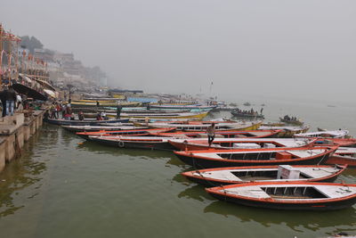 Boats moored at harbor against sky