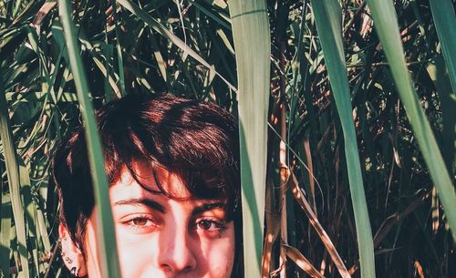 Portrait of young woman amidst plants during sunny day