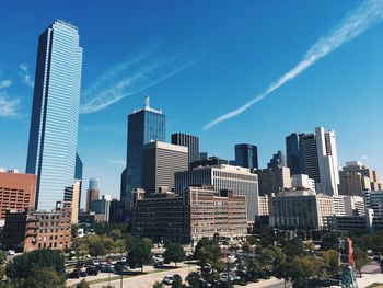 Low angle view of modern buildings against blue sky on sunny day in city