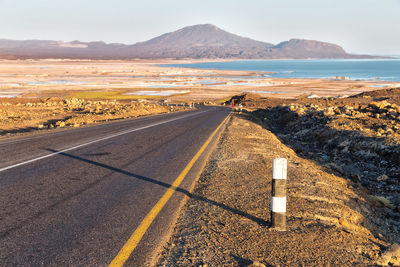Scenic view of road by sea against sky