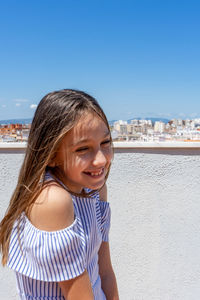 Portrait of smiling girl standing against clear sky