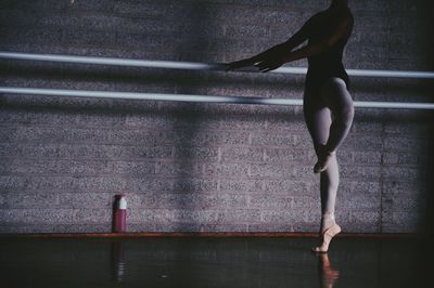 Low section of young woman dancing on floor at ballet studio