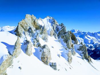 Scenic view of snow covered mountains against clear blue sky