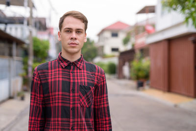 Portrait of young man standing against building