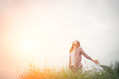 Woman standing on field against sky during sunset