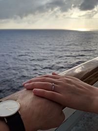 Midsection of woman hand by sea against sky