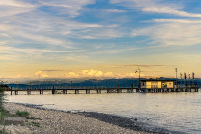 Pier at harbor against sky during sunset