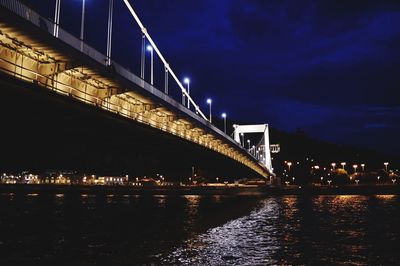 Illuminated bridge over river against sky at night