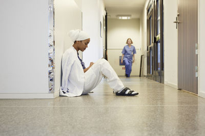 Female doctor sitting on hospital corridor floor