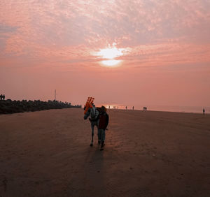 Rear view of couple on beach during sunset