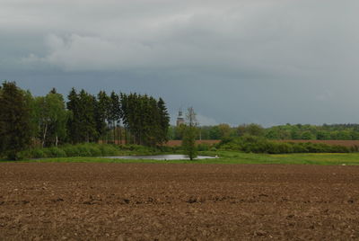 Trees on field against cloudy sky