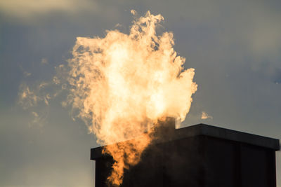 Fire on building against cloudy sky during sunset