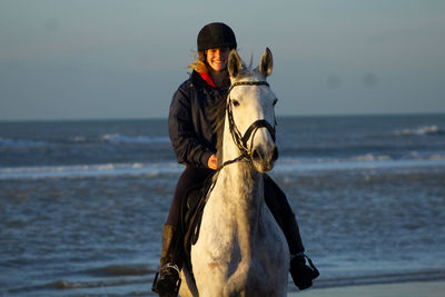 Smiling woman horseback riding at beach