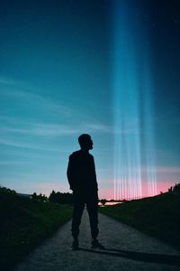 Rear view of man standing on road at night