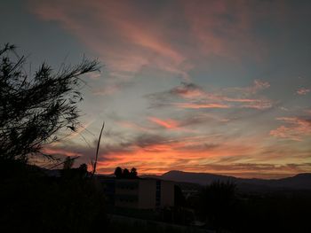 Silhouette houses against sky during sunset