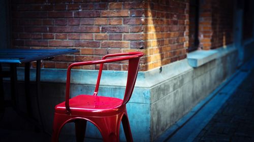 Empty chair by brick wall
