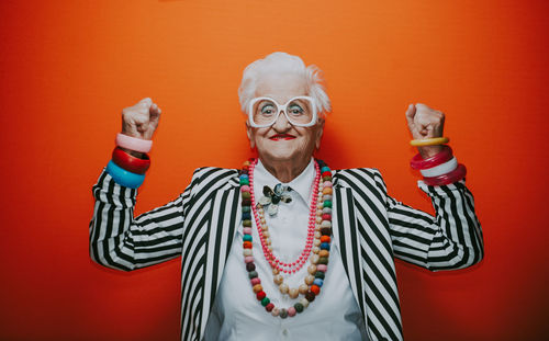 Portrait of smiling senior woman dancing against red background