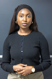 Portrait of young woman standing against wall