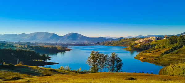 Scenic view of lake and mountains against blue sky