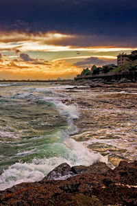 Scenic view of sea against cloudy sky during sunset