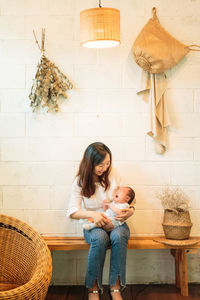 Happy mother with baby sitting on bench indoors