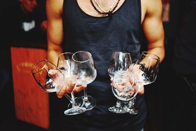 Midsection of man holding wine glass on table