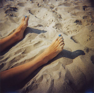 Low section of person relaxing on sand at beach