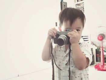 Portrait of baby boy photographing with camera at home