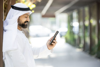 Smiling man using mobile phone while standing on street