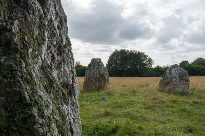 View of rocks on field against cloudy sky