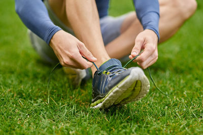 Low section of man tying shoelace