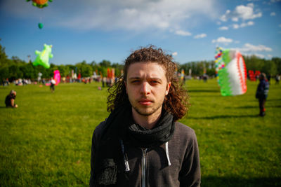 Portrait of man standing in park against cloudy sky