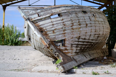 Abandoned boat on field against sky