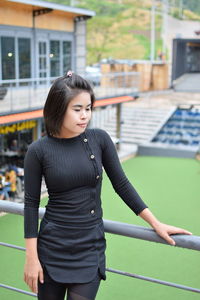 Thoughtful young woman looking away while standing by railing on observation point