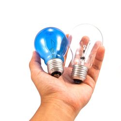 Close-up of hand holding light bulb against white background