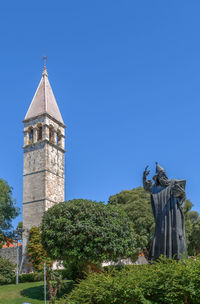 Trees and historic building against clear blue sky