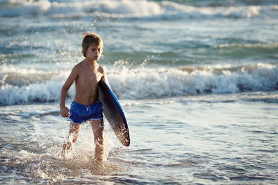 Full length of shirtless boy on beach